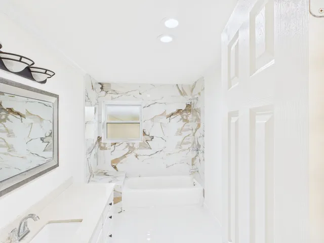 a bathroom with a bathtub sink and mirror