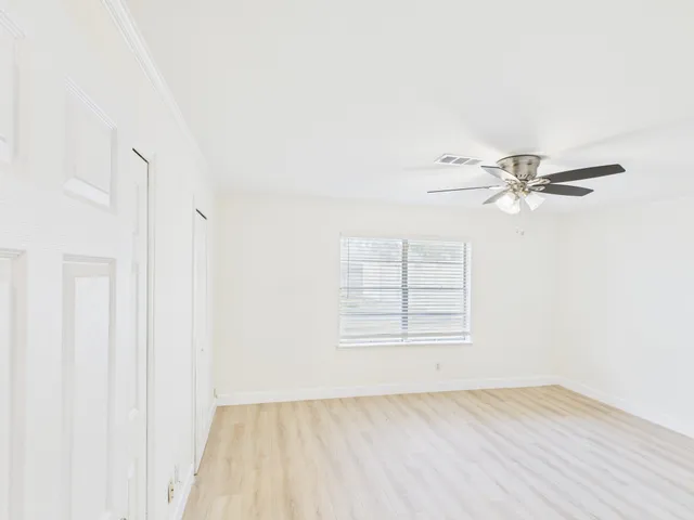 an empty room with windows and fan