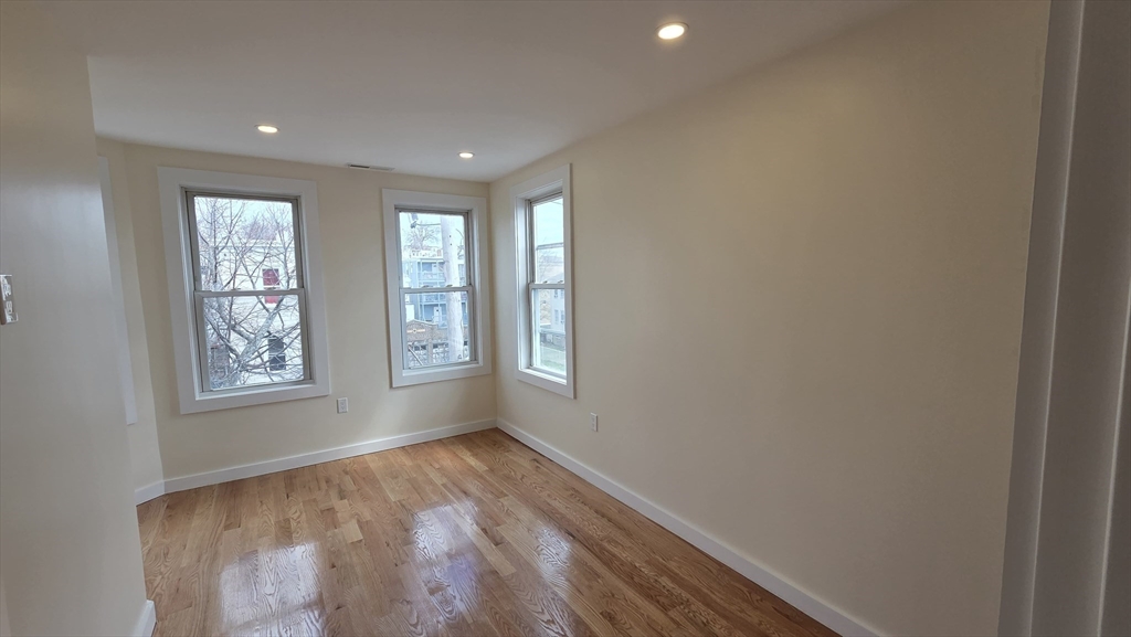 125 Central Avenue, Unit 3 Chelsea, MA 02150 - Photo 3 of 13 an empty room with wooden floor and windows