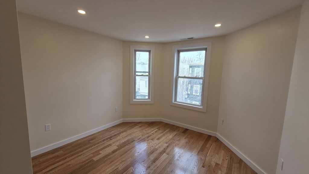 125 Central Avenue, Unit 3 Chelsea, MA 02150 - Photo 5 of 13 an empty room with wooden floor and windows