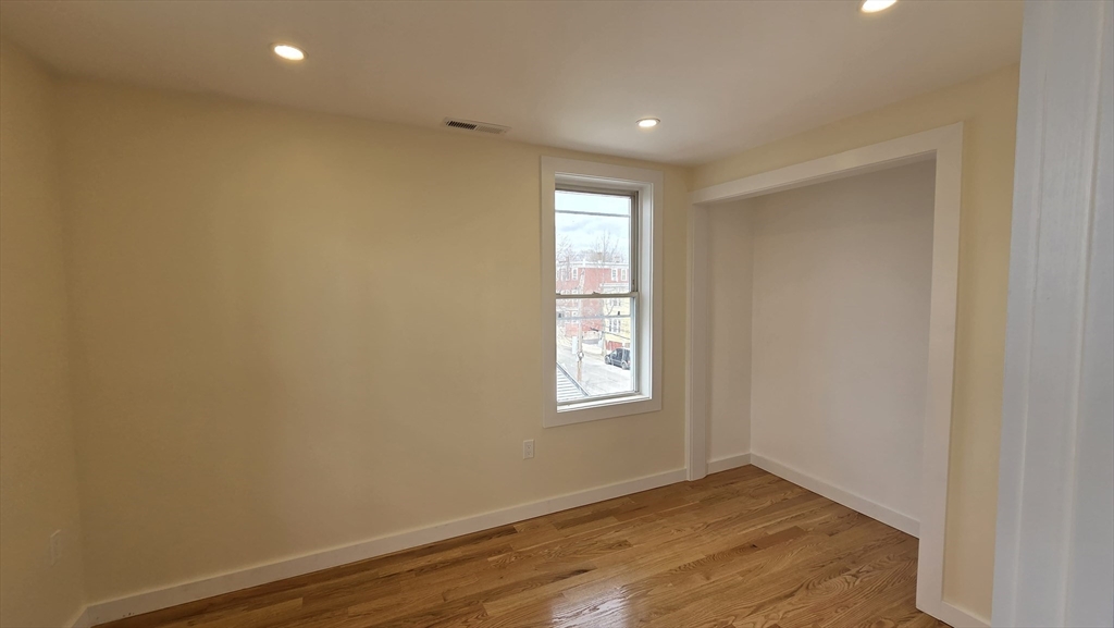125 Central Avenue, Unit 3 Chelsea, MA 02150 - Photo 6 of 13 an empty room with wooden floor and windows
