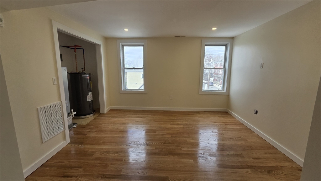 125 Central Avenue, Unit 3 Chelsea, MA 02150 - Photo 7 of 13 an empty room with wooden floor and windows