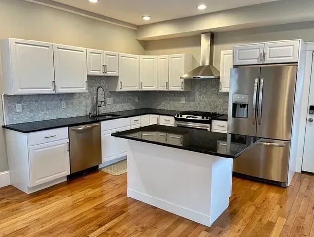 a kitchen with granite countertop a refrigerator and a stove top oven