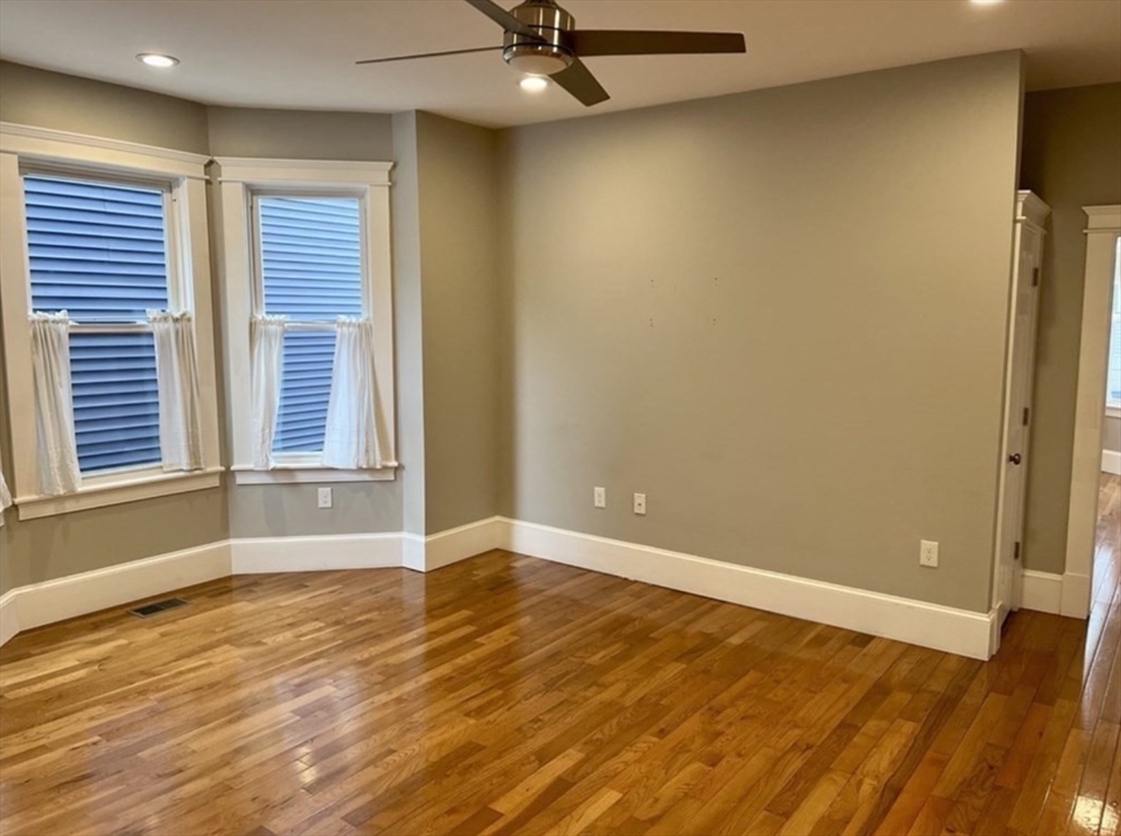 16 East Cottage Street, Unit 1 Boston, MA 02125 - Photo 4 of 10 an empty room with wooden floor and windows