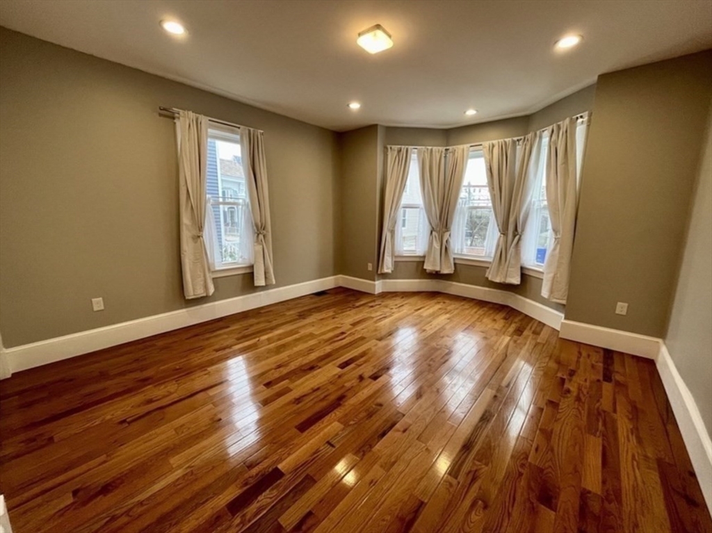 16 East Cottage Street, Unit 1 Boston, MA 02125 - Photo 5 of 10 a view of an empty room with wooden floor and a window