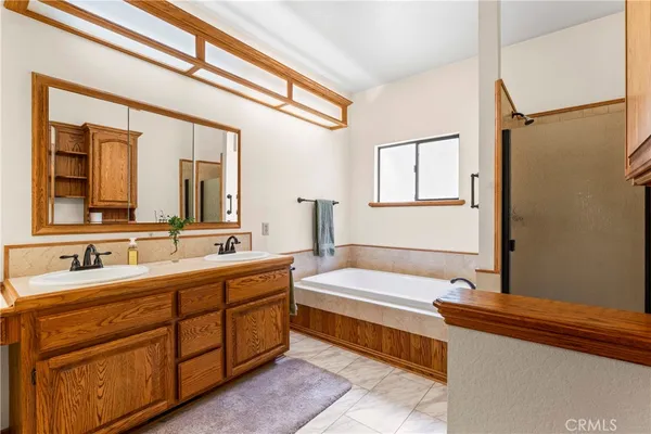 a spacious bathroom with a double vanity sink a large mirror and a bathtub