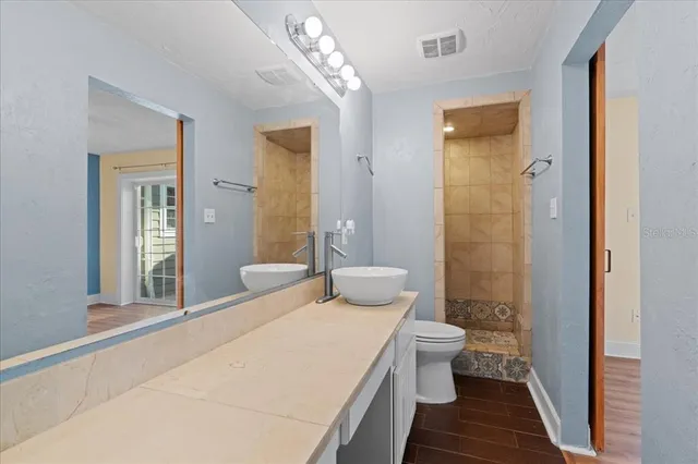 a bathroom with a sink a toilet a mirror and shower