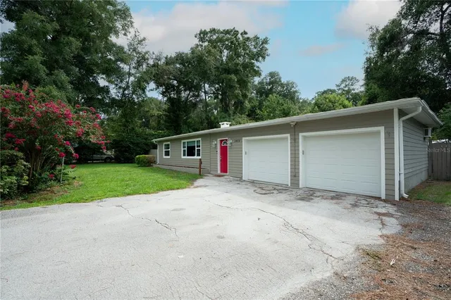 a view of a house with a yard and large trees