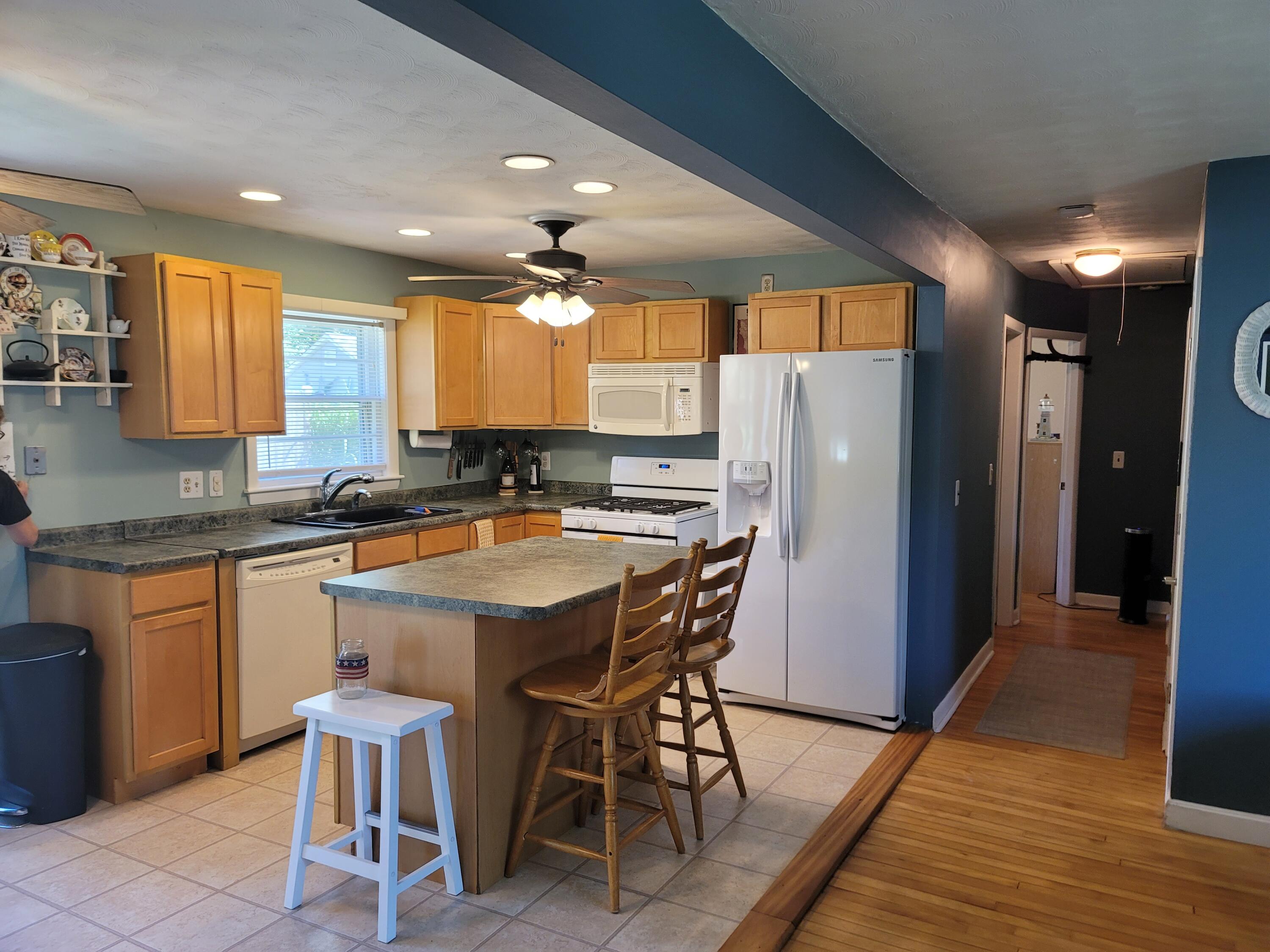 55 Clay Pond Road Monument Beach, MA 02532 - Photo 2 of 15 a kitchen with stainless steel appliances granite countertop wooden floor a refrigerator a sink and white cabinets