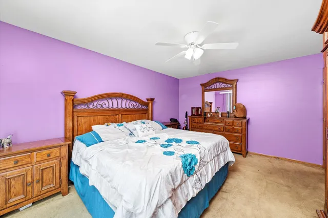 a bedroom with a bed a chandelier and pink walls