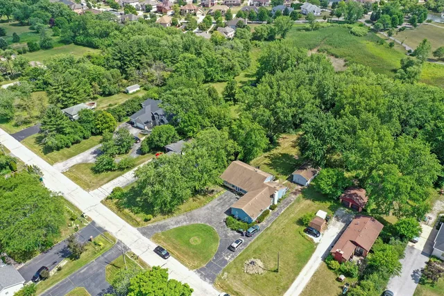 an aerial view of residential house with outdoor space and trees all around
