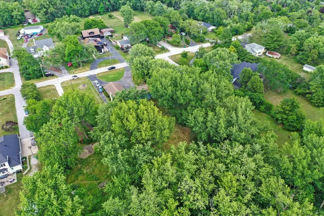 an aerial view of residential house with outdoor space and trees all around