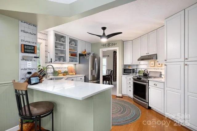 a kitchen with a refrigerator a stove a sink dishwasher a dining table and chairs with wooden floor