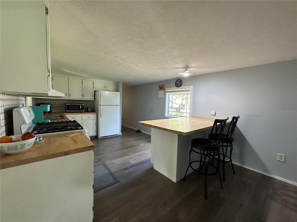 55045 6th Street Astor, FL 32102 - Photo 4 of 38 a kitchen with stainless steel appliances granite countertop a stove a sink a refrigerator a dining table and chairs with wooden floor