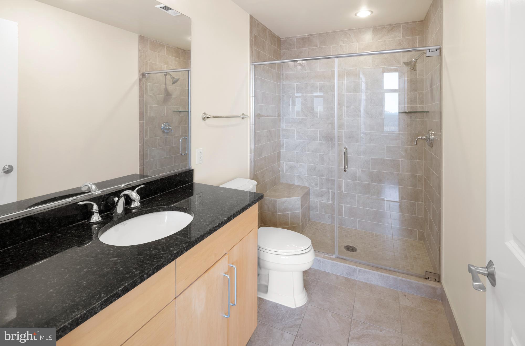 8220 Crestwood Heights Drive, Unit 1215 McLean, VA 22102 - Photo 23 of 59 a bathroom with a granite countertop sink a toilet a mirror and shower