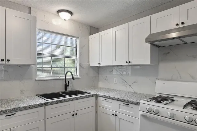 a kitchen with granite countertop white cabinets sink and window
