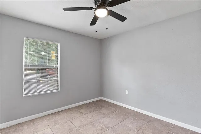 an empty room with windows and fan