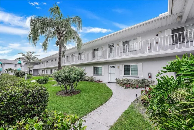 a front view of a house with a yard and potted plants