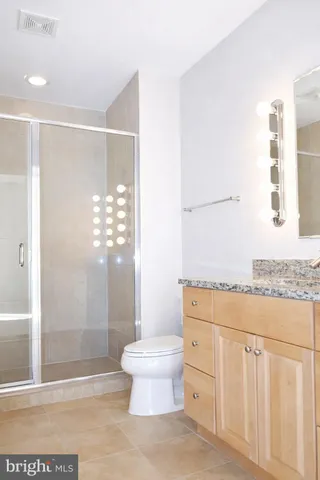 a bathroom with a granite countertop sink a toilet and shower