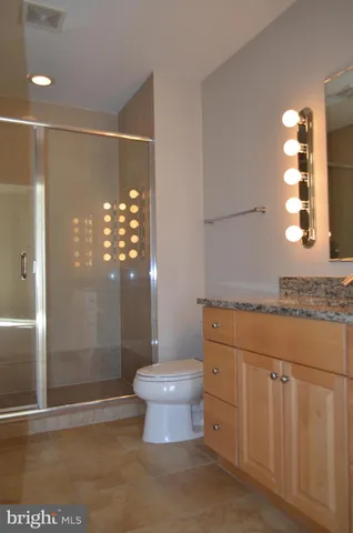 a bathroom with a granite countertop sink a toilet and shower