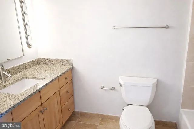a bathroom with a granite countertop toilet and a sink