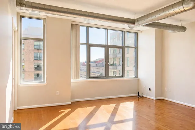 a view of an empty room with a window and wooden floor