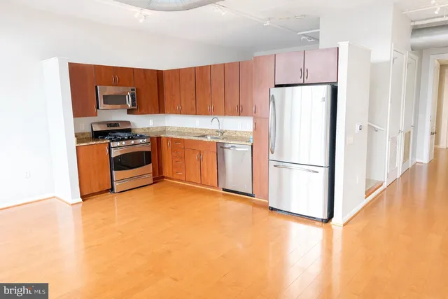 a kitchen with stainless steel appliances granite countertop a refrigerator a stove and a sink