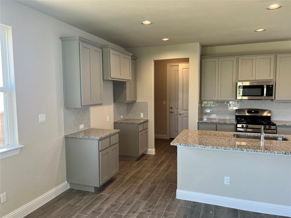 128 Free Stone Drive Georgetown, TX 78628 - Photo 8 of 29 Kitchen featuring light gray cabinetry, granite countertops, subway tile backsplash, and stainless steel appliances