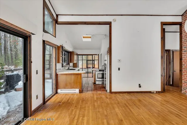 a view of a hallway with wooden floor and a living room