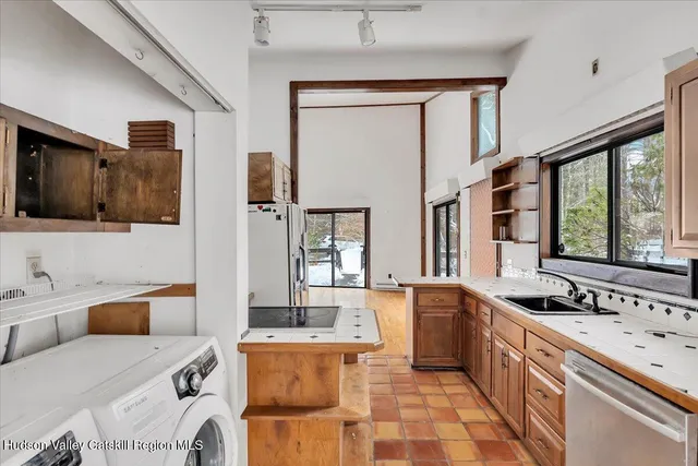 a large white kitchen with a sink large window and stainless steel appliances