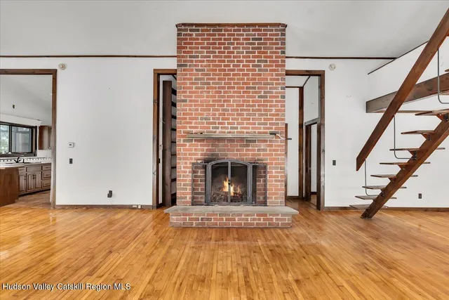 a view of a livingroom with wooden floor and a fireplace