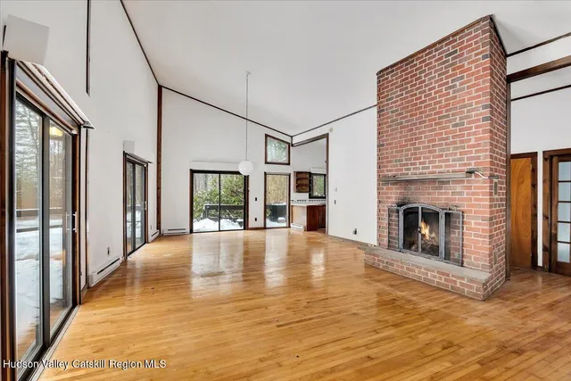 a view of an empty room with fireplace and wooden floor