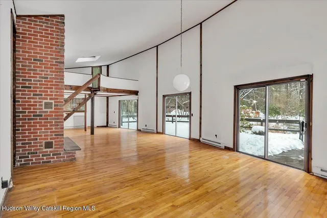 a view of an empty room with window and wooden floor