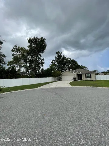 a view of a house with a big yard and large trees