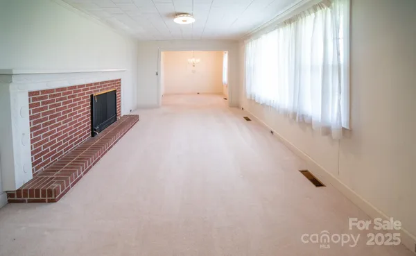 a view of an empty room with a fireplace and a window