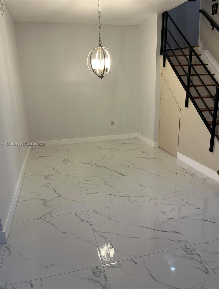 10150 Southwest 88th Street, Unit 103 Miami, FL 33176 - Photo 13 of 29 a view of an empty room with wooden floor and chandelier