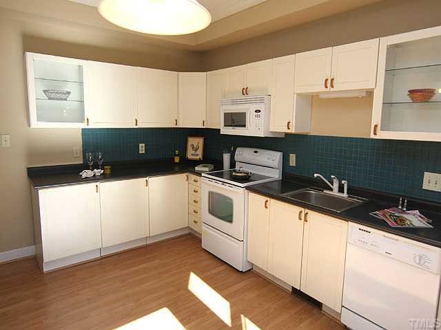 1318 Slatestone Court Raleigh, NC 27615 - Photo 4 of 12 a kitchen with granite countertop white cabinets and white appliances