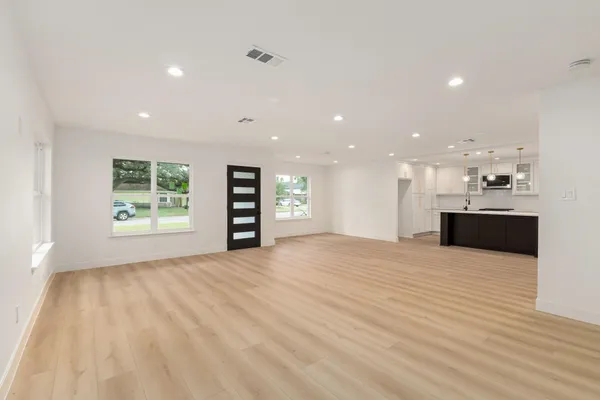 a view of an empty room with a window and kitchen view