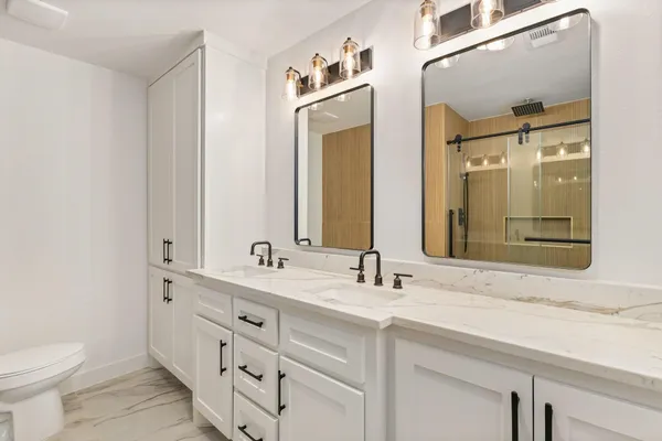 a bathroom with a double vanity sink mirror and toilet