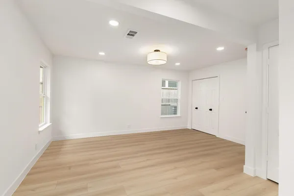 an empty room with wooden floor and windows