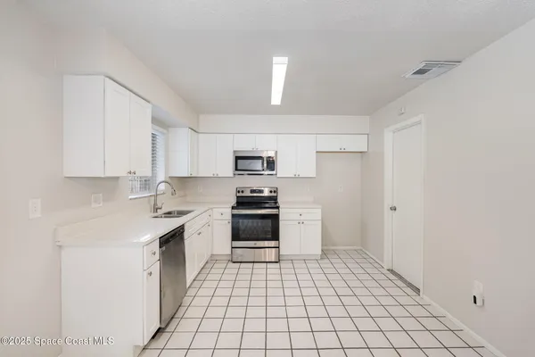 a kitchen with stainless steel appliances a stove a sink and white cabinets