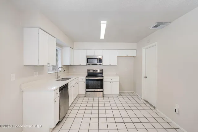 a kitchen with stainless steel appliances a stove a sink and white cabinets