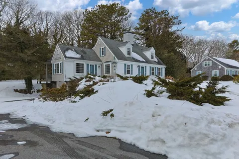 front view of a house with a yard covered in snow