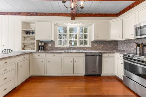 a kitchen with granite countertop a stove a sink and dishwasher