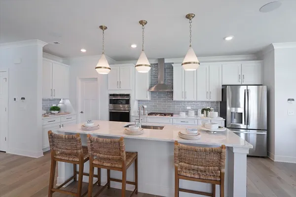 a kitchen with stainless steel appliances granite countertop a sink a stove a refrigerator cabinets a dining table and chairs