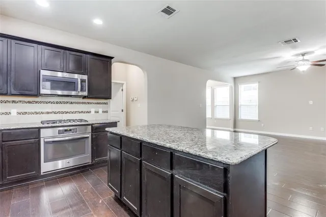 a kitchen with stainless steel appliances granite countertop wooden cabinets a stove a sink and a microwave