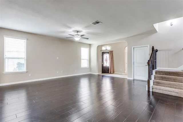 a view of an empty room wooden floor and a kitchen