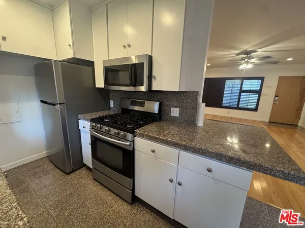 a kitchen with stainless steel appliances granite countertop a sink a stove and a refrigerator
