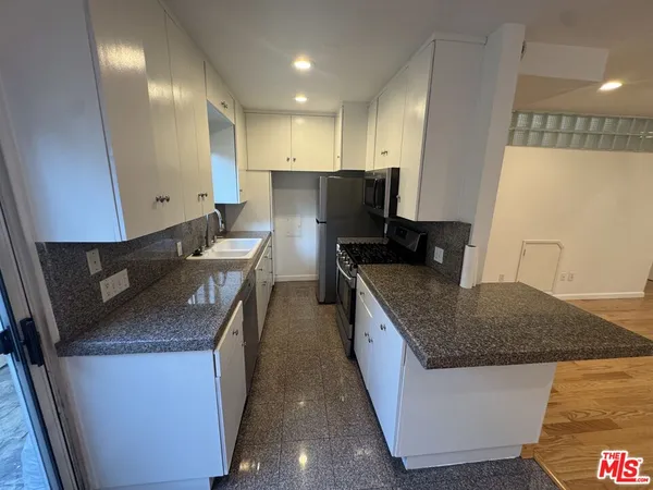 a kitchen with granite countertop a sink a counter top space and cabinets