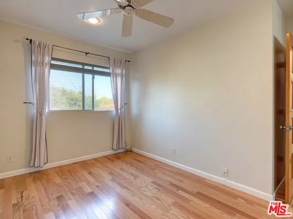 an empty room with wooden floor fan and windows